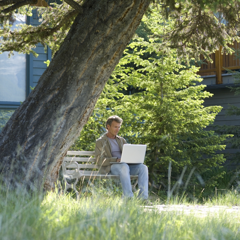 man using laptop under tree