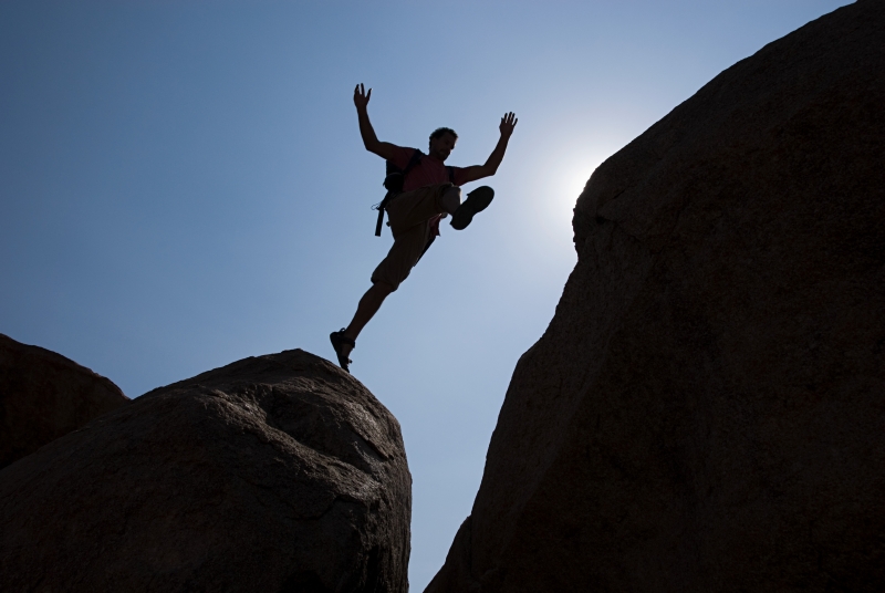 man jumping chasm represents the divide between data management and analytics