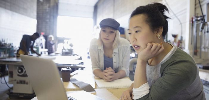 Businesswomen studying laptop, considering value of data literacy