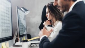 Coworkers study computer screens to understand data classification, governance and compliance process