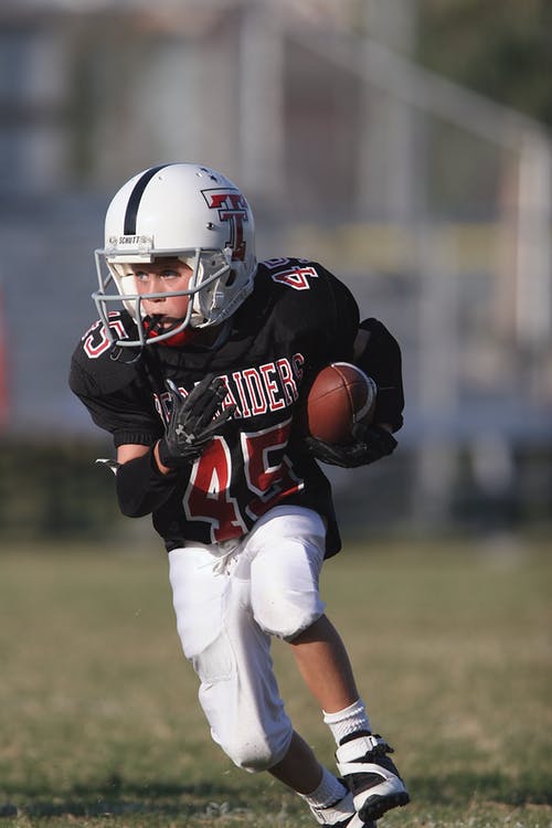 Boy playing football (photo compliments of Pexels)