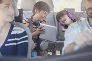 Happy brother and sister using digital tablet in back seat of car