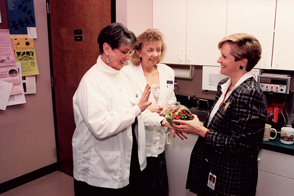 Jimmie Butts, Pat Crist and Gale Adcock in SAS breakroom with a jar of M & M's