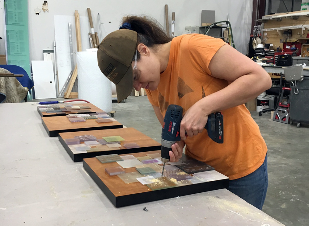 Juliana Craig drills acrylic squares onto wood to create her art piece "Array."