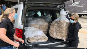 Bess and another volunteer unload food from an SUV