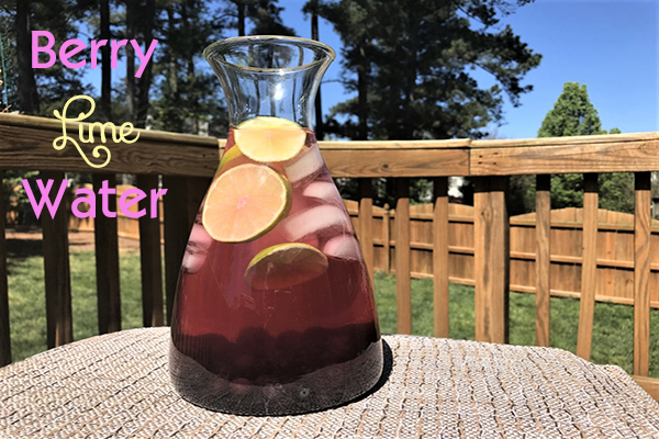 clear glass pitcher of blueberry and lime infused water outdoors