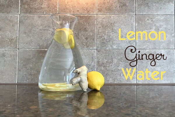 clear glass pitcher of water with lemon and ginger root
