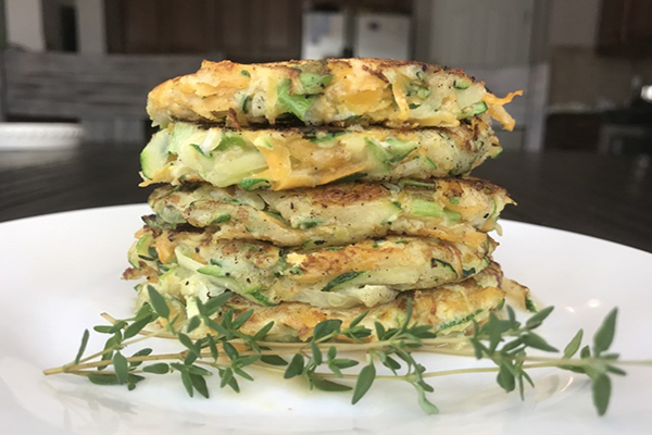 side view of a stack of 5 zucchini butternut squash pancakes with a sprig of thyme