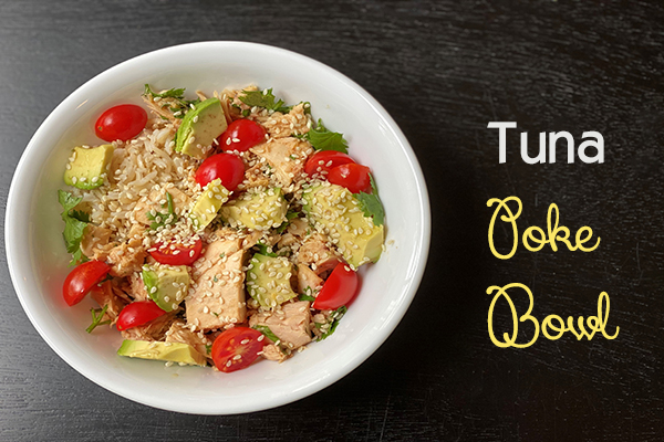 tuna, rice, avocado tomatoes and rice topped with sesame seeds in a white bowl
