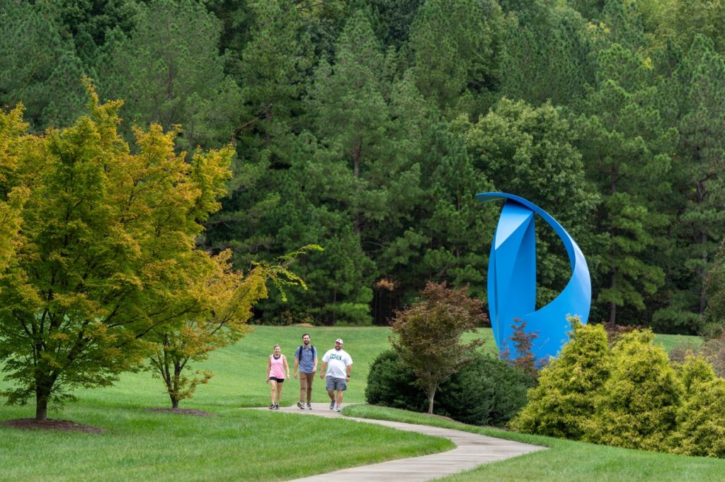SAS employees walking on a trail beside a large blue art sculpture