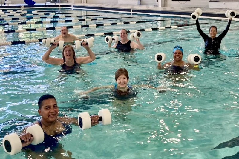 Employees pose for a photo in the pool after a water aerobics class