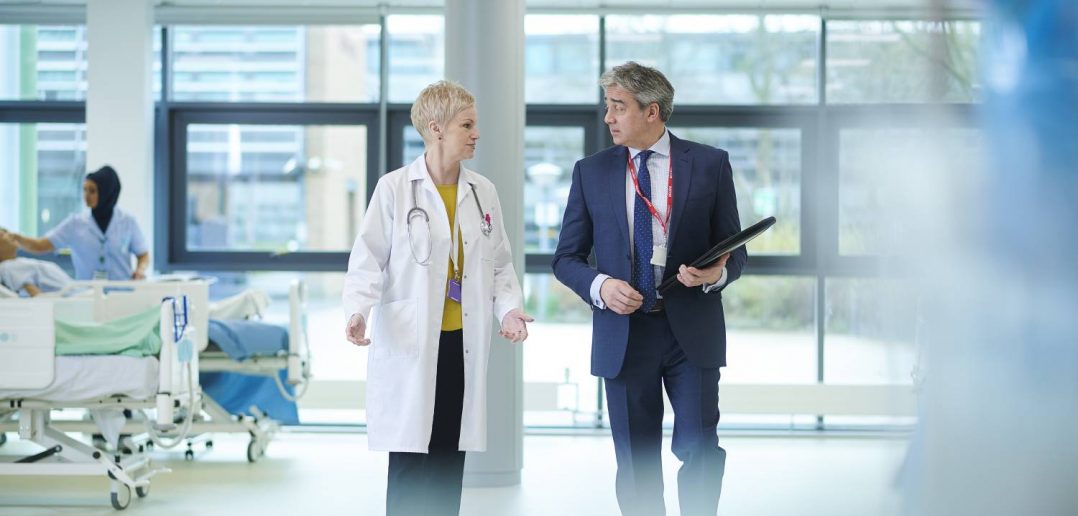 doctor and businessman walking through hospital