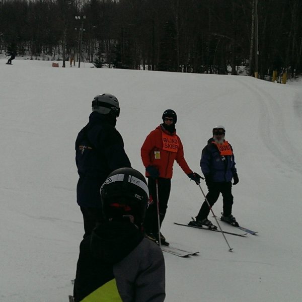 Ed is skiing with the help of Adaptive Sports Center instructors