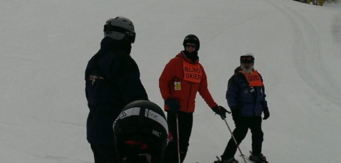Ed is skiing with the help of Adaptive Sports Center instructors