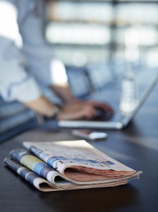 Newspapers in foreground with laptop 