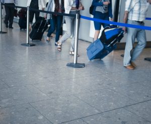 travelers pulling suitcases through an airport security line