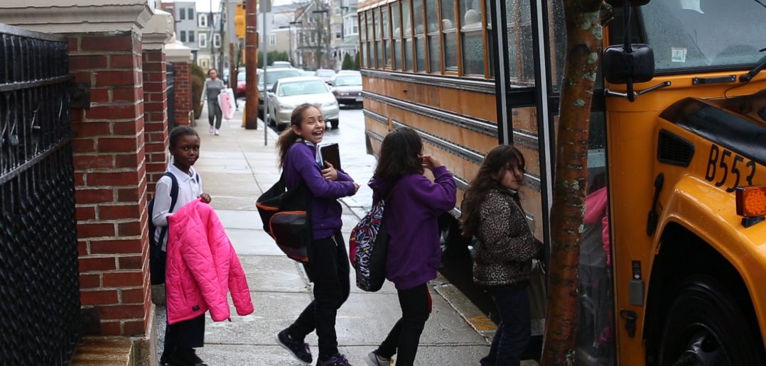 Students boarding school bus from city sidewalk