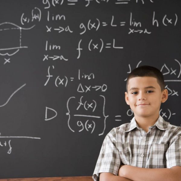 Young man standing in front of chalkboard with statistical functions