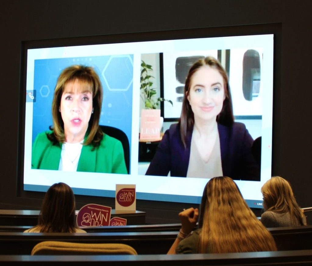 Three women watch a live streamed interview of Galica in a conference room.