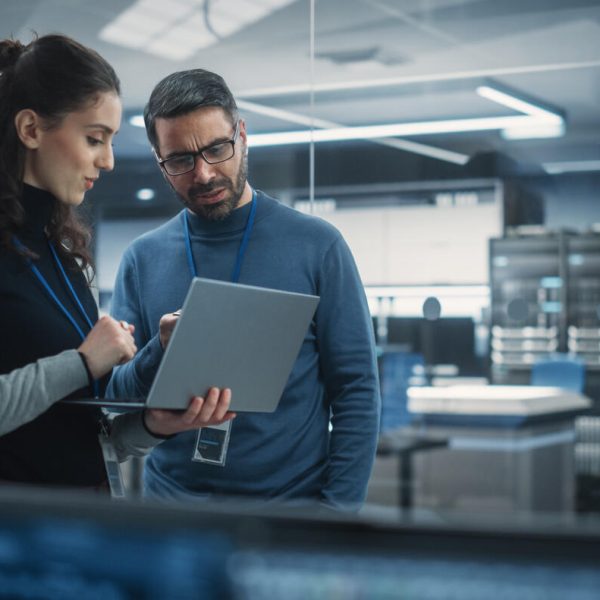 Portrait of Two Female and Male Engineers Using Laptop Computer