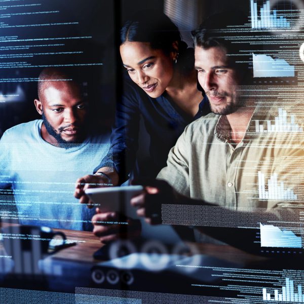 Shot of a group of programmers using a digital tablet while working together on a computer code at night