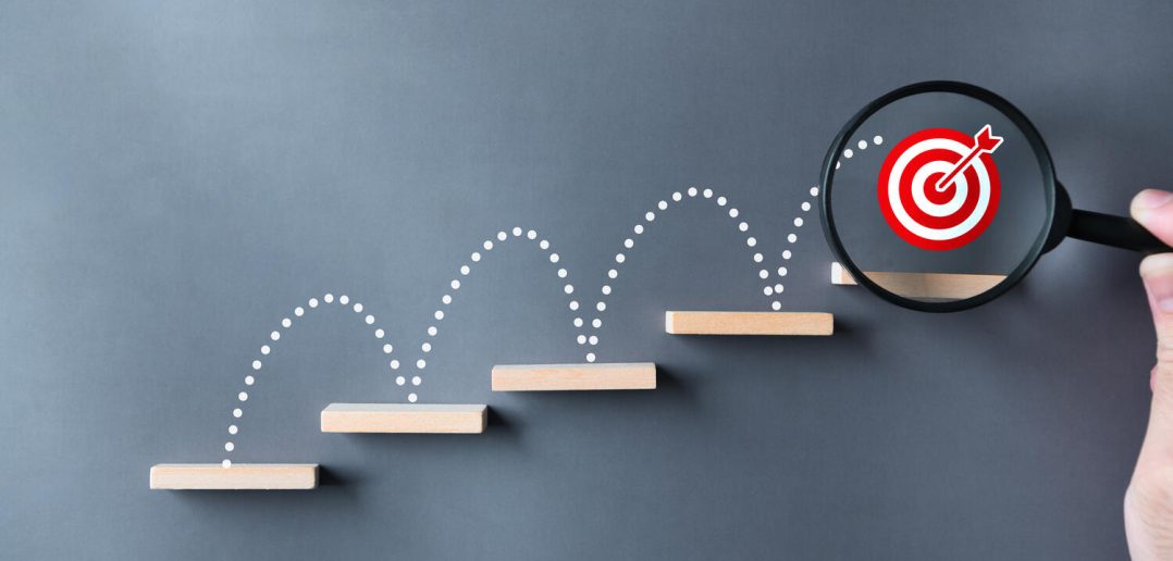 Unlock potential of business success stairs dart and dartboard targets magnifying glass with hand on gray background. Explore opportunities growth embrace steps to achieve ambitions and goal concept.