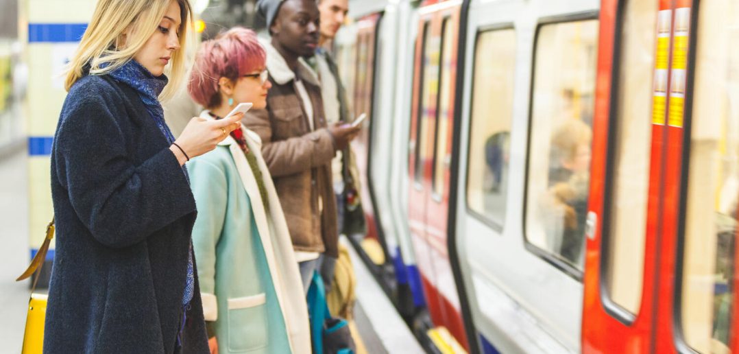 People waiting for the train at subway station. Mixed race persons, two men and two women, staying on a line and waiting to board the train. Commuting and transport