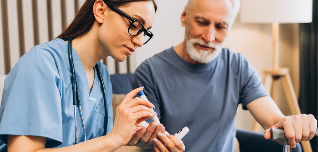 Healthcare professional assisting an elderly man with diabetes, performing a routine blood glucose test for home care monitoring