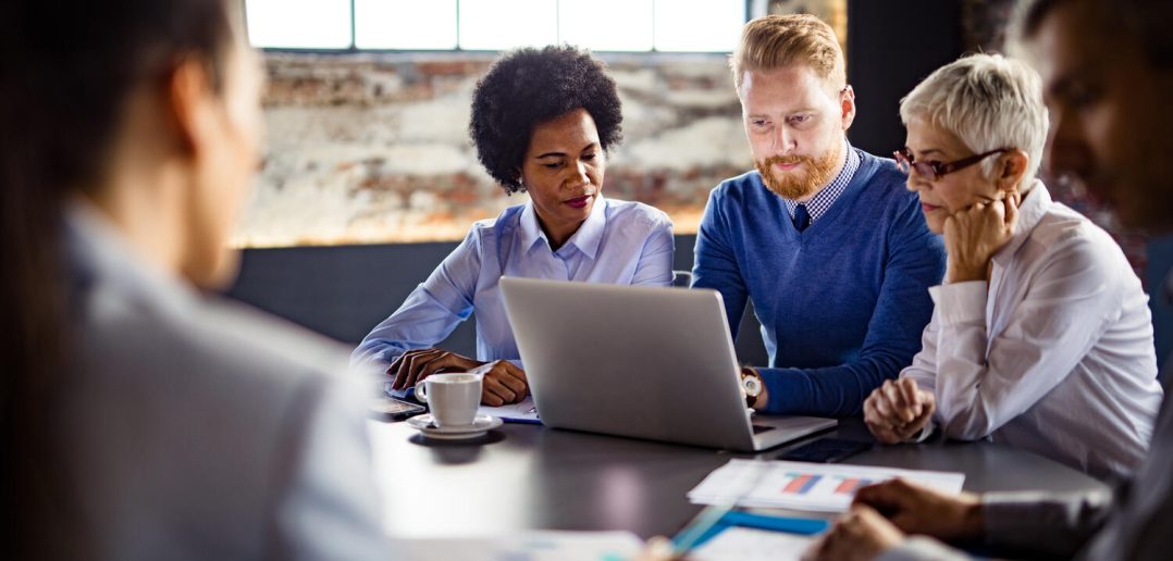 Group of business people working on a computer during a meeting in the office -- team of business colleagues working on laptop in the office