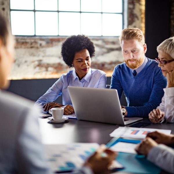 Group of business people working on a computer during a meeting in the office -- team of business colleagues working on laptop in the office