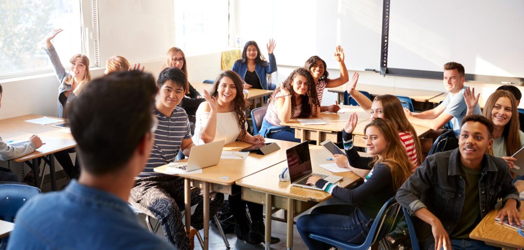 Rear View Of Male High School Teacher Standing At Front Of Class Teaching Lesson