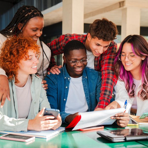 A diverse group of focused students actively collaborating on an exciting academic project with documents and devices, showcasing teamwork and engagement in a learning environment.