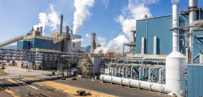 Entire industrial plant with smoke rising out of stacks.